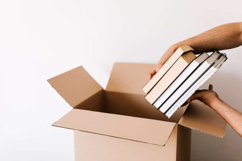Un déménageur transporte des cartons de déménagement remplis de livres