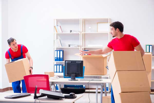 Deux déménageurs sont en train de déménager un bureau.